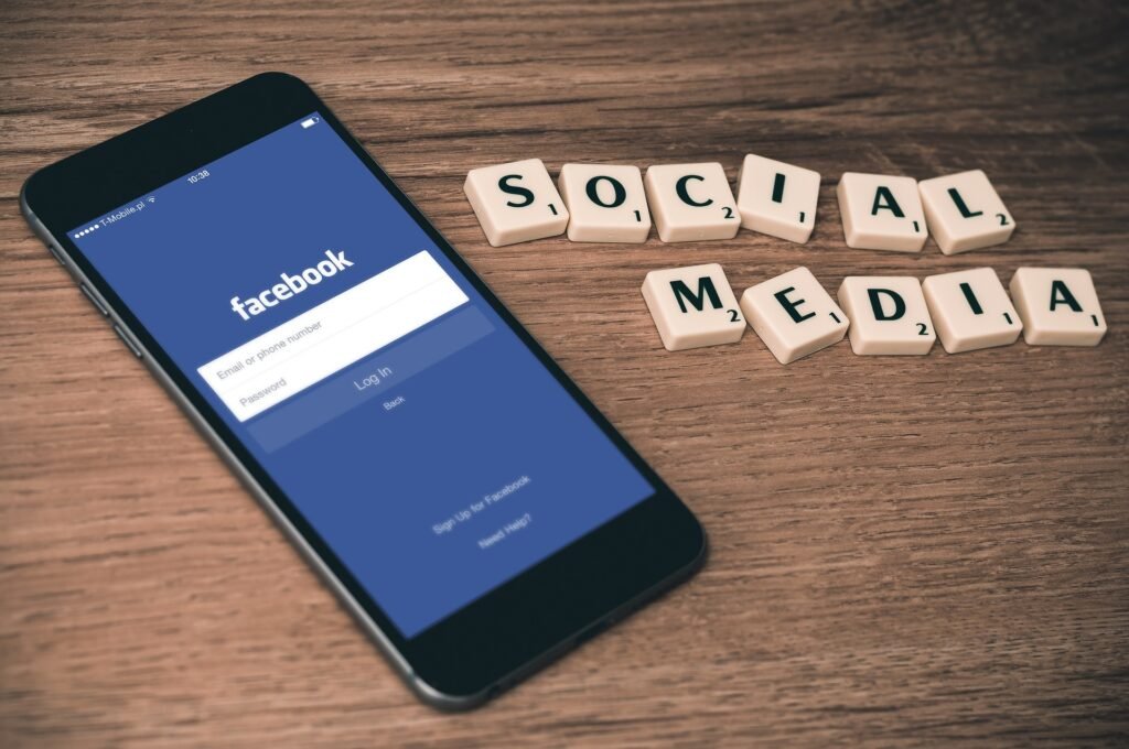 Facebook ads interview questions concept shown with a smartphone displaying Facebook login screen and social media text tiles on a wooden background